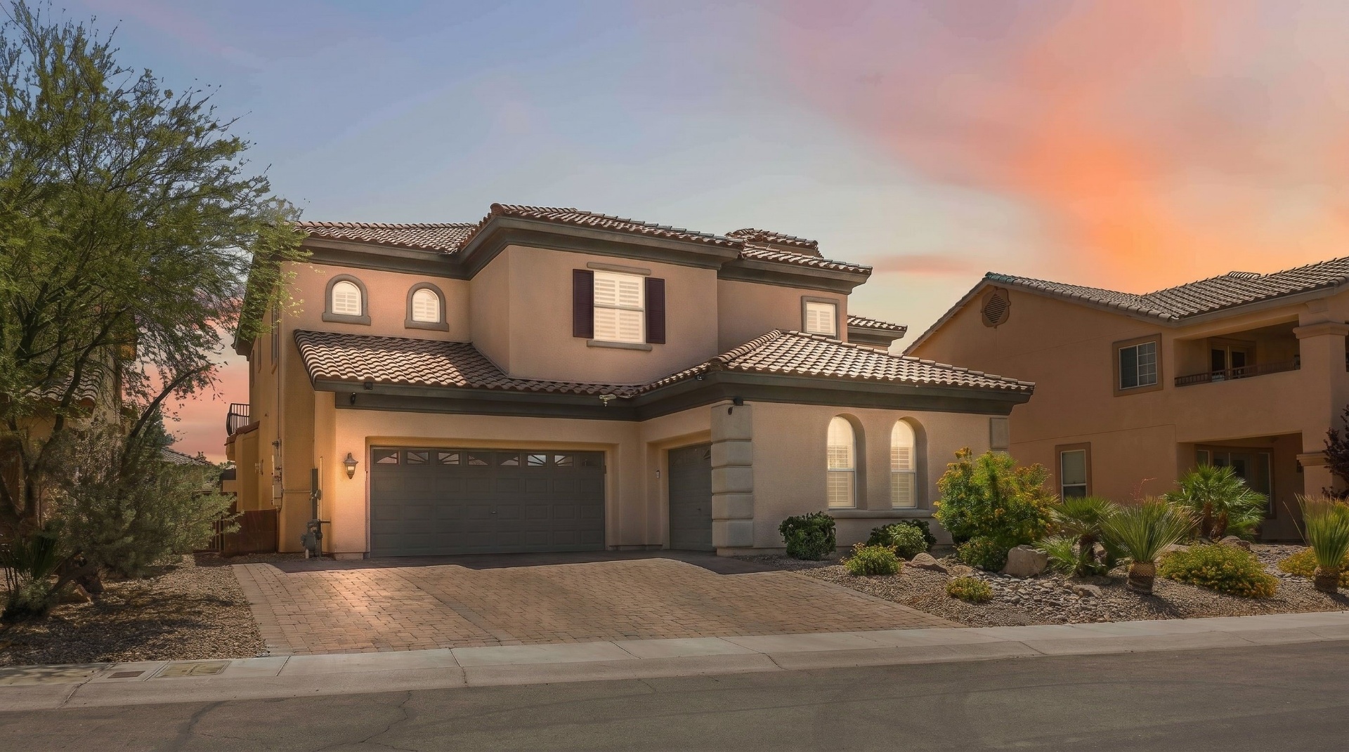 9564 Trattoria Street at twilight — Tuscan-style luxury home with barrel-tile roof and paver driveway