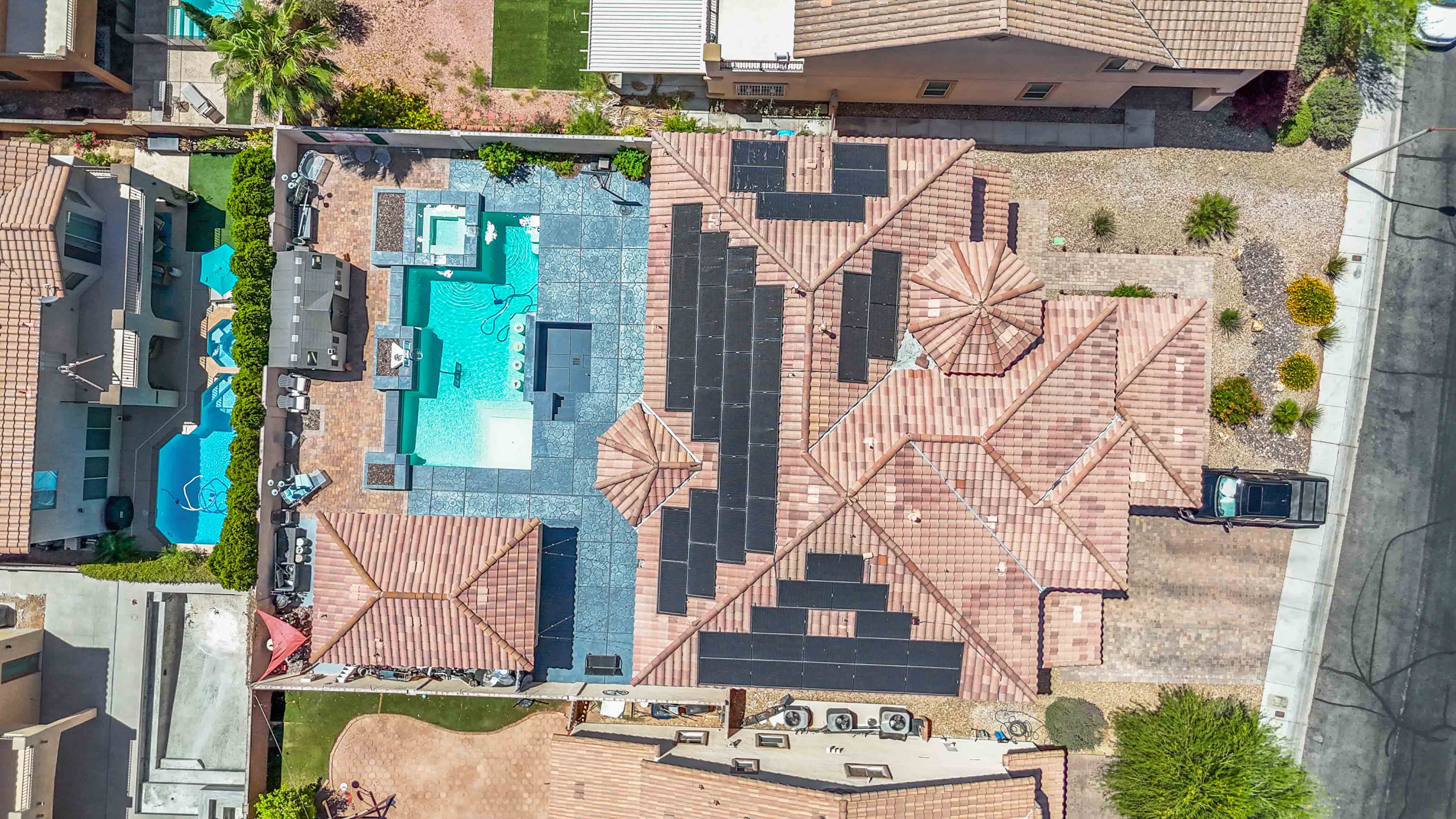 Aerial view of the backyard side of 9564 Trattoria Street with pool and solar roof panels
